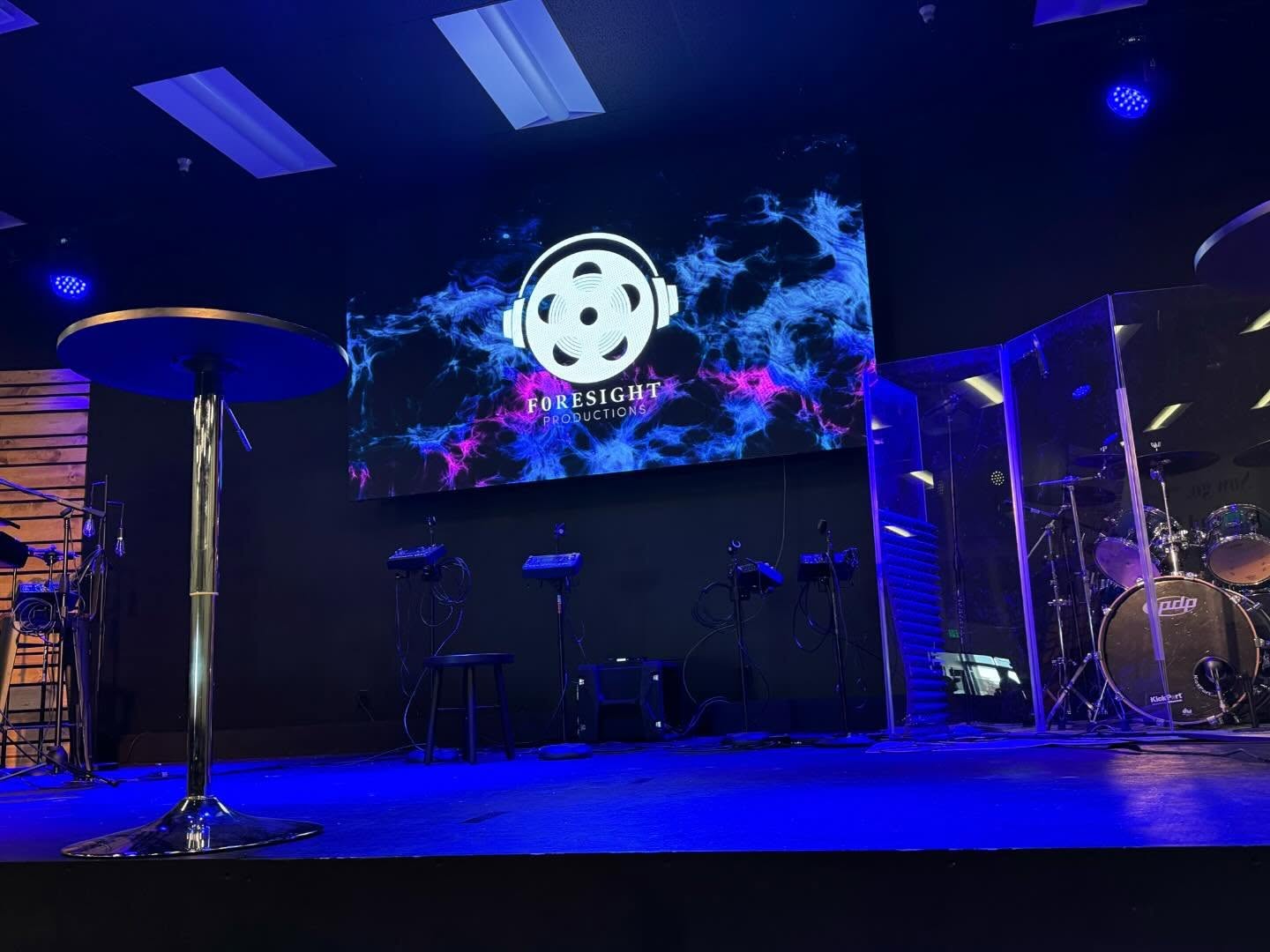 Side view of a church worship stage with an LED video wall and drum enclosure